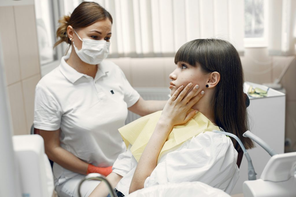 dentist and patient touching her jaw