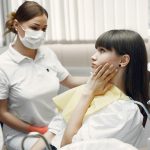 dentist and patient touching her jaw
